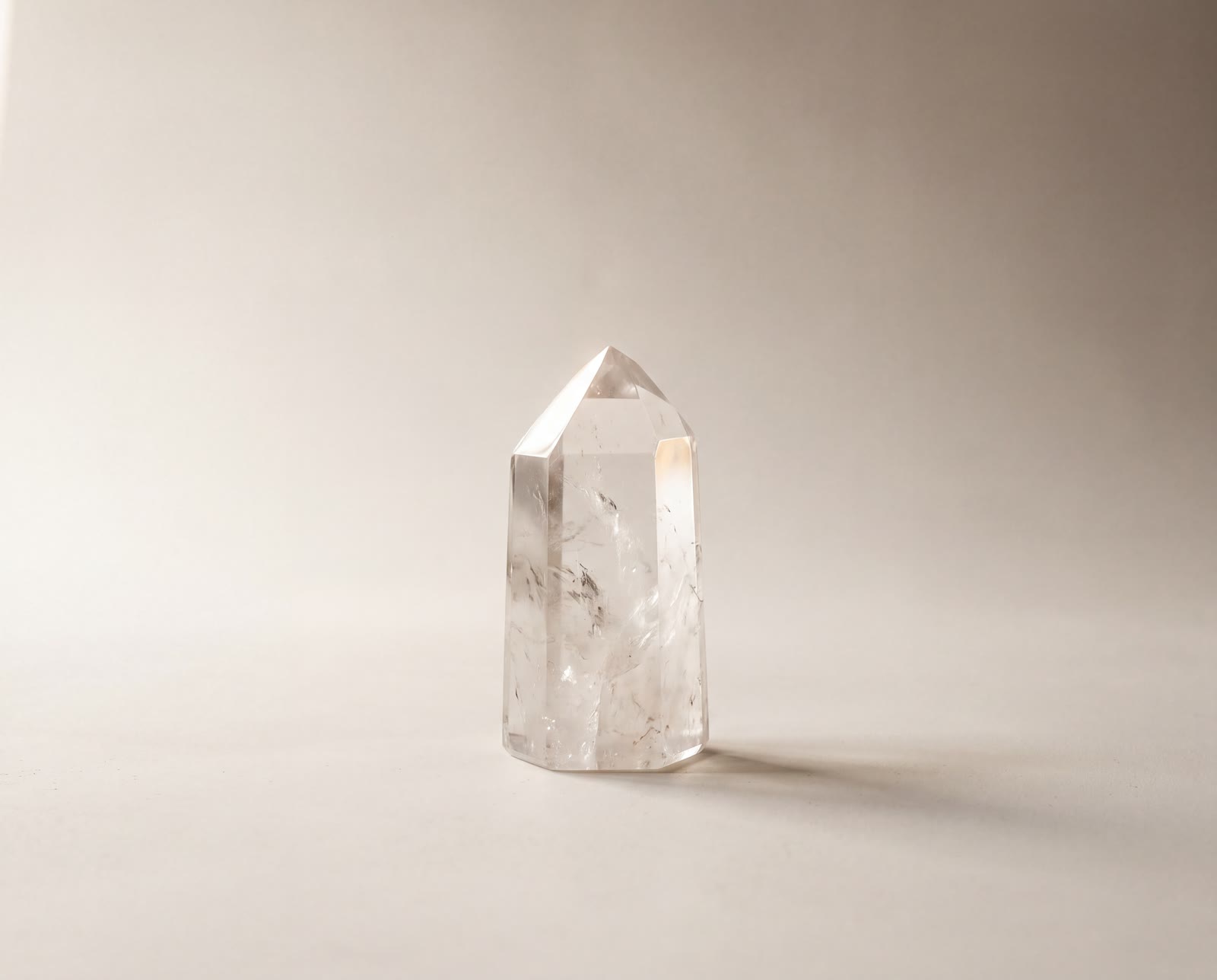 A polished clear quartz point standing upright in soft window light
